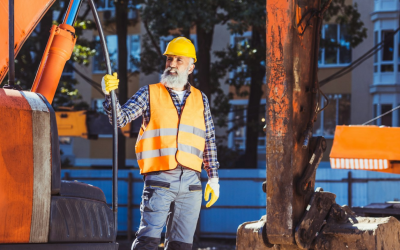 Image – Worker in reflective vest and hardhat standing in front of excavator at construction site Image - Worker in reflective vest and hardhat standing in front of excavator at construction site